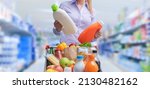 Small photo of Woman doing grocery shopping at the supermarket and comparing products, she is checking two bottles of laundry detergent