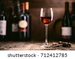 Wine tasting experience in the rustic cellar and wine bar: red wine glass and collection of excellent wines on the background