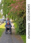 Small photo of Knutsford, Cheshire, UK. 2nd June 2023. Customer with attendant in self propelled wheelchair hired from the Red Cross Mobility Aids Service, Knutsford, Cheshire, UK