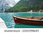 A wooden ship among natural landscape view of Lake Lago di Braies with Dolomiti (Dolomites) snowy mountain range- South Tyrol, Italy