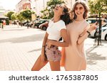 Two young beautiful smiling hipster girls in trendy summer clothes.Sexy carefree women posing on the street background in sunglasses. Positive models having fun and going crazy