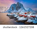 Famous tourist attraction Hamnoy fishing village on Lofoten Islands, Norway with red rorbu houses. With falling snow in winter on sunrise