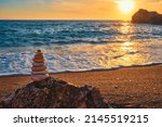 Small photo of Concept of balance and harmony. Cairn stack of stones pebbles cairn on the beach coast of the sea in the nature on sunset. Meditative art of stone stacking