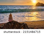 Small photo of Cairn stack of stones pebbles cairn on the beach coast of the seaon sunset. Agios Ioannis beach, Milos island, Greece