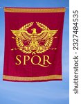 Small photo of red banner in vertical view with a symbol from ancient roma, formed by an eagle and a laurel wreath and the legend SPQR. Senatus Populus que Romanus