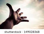 Hand of a man reaching to towards sky. Color toned image.