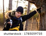 Small photo of Funny young man leaning in the tree thunk and grimacing, trying to amuse you