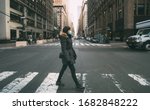 Small photo of Woman wearing surgical mask going through crosswalk in midtown manhattan.Concept of Coronavirus, COVID-19 and quarantine