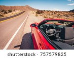 Red convertible with the top down stopped on a shoulder on a desert road