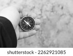 Small photo of Old classic navigation compass in hand on natural background as symbol of tourism with compass, travel with compass and outdoor activities with compass