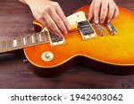 Small photo of Guitar master adjusts intonation on electric guitar at his workplace.