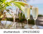Two glasses of chilled prosecco over tropical background