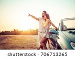Happy couple standing next convertible car and looking away 