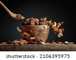 Flying dried fruits and nuts. The mix of dried nuts and raisins in a wooden bowl. Copy space.