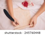 Love letter. Closeup image of woman writing a vintage letter with copy space to valentines day with feather pen while lying in bed
