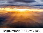 amazing dramatic cloudscape in sunset with sun rays over misty mountains landscape  
