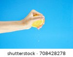 woman Hand Squeezing a Half fresh Lemon isolated on blue background