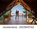 Small photo of Rear view of amorous couple standing close to each other and looking at blue ocean while enjoying summer vacation