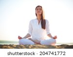 Meditating woman sitting in pose of lotus against clear sky outdoors