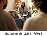 Small photo of Young social worker in suit sitting on sofa in the living room and talking to foster parents about custody at meeting at home