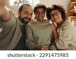 Small photo of Portrait of happy family with adopted daughter smiling at camera while making selfie portrait