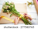 Female florist tying up fresh bouquet with yellow ribbon