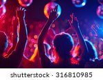 Group of young people with raised arms dancing in night club