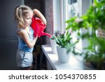 little girl is watering flowers ... | Shutterstock . vector #1054370855