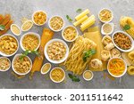 Pasta. Various kinds of uncooked pasta and noodles over stone background, top view with copy space for text. Italian food culinary concept. Collection of different raw pasta on cooking table