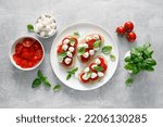 Small photo of Caprese toasts with mini mozzarella cheese, cherry tomato and basil, top view