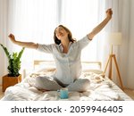 Happy young woman enjoying sunny morning on the bed.  