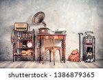 Antique chair, old typewriter, retro radio,  gramophone on wooden desk, books, clock, camera, binoculars, fiddle, keys on shelf, mask, cylinder hat, shoes, cane, backpack. Vintage style filtered photo