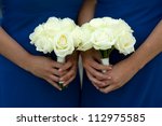 bridesmaids in blue dresses holding a white rose wedding bouquet