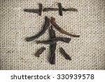 Small photo of Chinese logogram Tea made of tea leaves on flax background close up