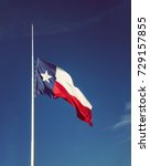 Small photo of State flag of Texas flying at half-mast or half-staff on a flagpole. Blue sky background with copy space.