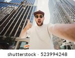 Happy funny bearded man taking selfie and showing thumbs up in Manhattan. Hipster tourist posing for photo while travel in New York.