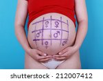 Small photo of Pregnant woman with painted naught and crosses game on belly