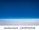 Small photo of The of a clear blue sky with a very flat featureless cloudy sky below as viewed from the window of a jet.