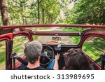 Couple in an ondtimer convertible, driving through the woods, carefree, enjoying the ride