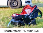 Small photo of Contented calm little baby in a carry cot outdoors in the garden on the grass looking at the camera, with copy space alongside