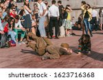 Small photo of MOSCOW, RUSSIA-MAY 09, 2015: People celebrate Victory Day May 9 in the Gorky Park. 2 cheerful child in uniform of World War II and one boy in casual clothes dance and tumble on the wooden floor in the