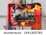 Small photo of Burning switchboard from overload or short circuit on wall close-up. Circuit breakers on fire from overheating due to poor connection or poor quality wires. Faulty home wiring concept