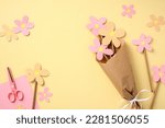 Bouquet of homemade paper flowers from cardboard on pastel yellow background. Mothers Day concept.
