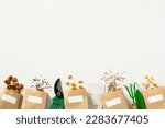 Small photo of Paper bags with different kinds of seeds and gardening supplies on a white background. Gardeners store banner template.