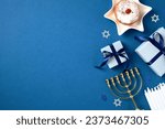 Small photo of Jewish holiday Hanukkah concept. Flat lay composition with traditional jelly donut, menorah, candles and gift boxes on blue background. Flat lay, top view.