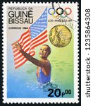 Small photo of GUINEA BISSAU - CIRCA 1984: post stamp printed in Guine Bissau shows national flag, gold medal and Tracie Ruiz, synchronized swimming, US; 1984 Olympic winners; Scott 614 A82 20p, circa 1984