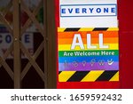 Small photo of The LGBT community stickers "All are welcome here" on the door in the old city in a sign of friendly neighborliness and hospitality for all types of gender people. somewhere in some city in Spain.