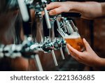 Small photo of bartender hand at beer tap pouring a draught beer in glass serving in a bar or pub. taproom