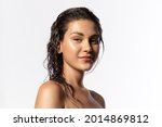 Beautiful young woman with clean perfect glowing skin, wet hairs. Portrait of smiling girl with bare shoulders on gray studio background. Skincare and wellness. Natural woman beauty.