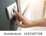 Small photo of Close up of Female finger is turning on or off on light switch over green wall covering. Copy space.